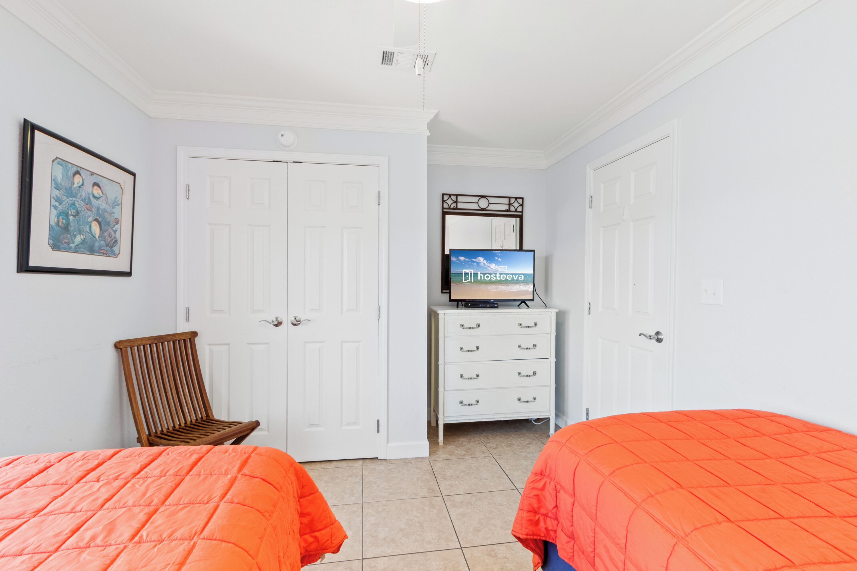 Habitación de hotel con dos camas, un televisor, una silla de madera y un aparador.