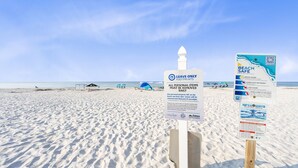 Ein Strand mit Schildern, die dazu auffordern, nur Fußabdrücke zu hinterlassen, und Sicherheitsrichtlinien für den Strand zeigen.