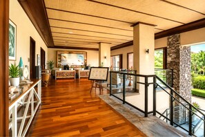 Eine Hotelhalle mit Holzboden, einer Rezeption, Kunstwerken und einer Treppe, die zu einem Außenbereich führt.