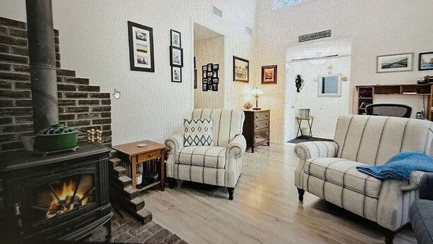 Una sala de estar acogedora con chimenea, un sofá, una silla y una mesita.