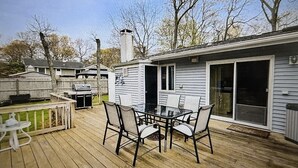 Una terraza con mesa y sillas, una parrilla y un cobertizo.
