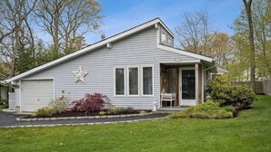 Una casa de un piso con garaje, una decoración de estrella en el lateral y un pequeño porche con una silla.