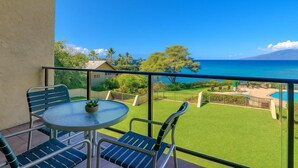 Ein Balkon mit Tisch und Stühlen, ein kleiner Pool und Blick auf das Meer und Grünflächen.