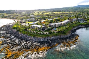 Eine Luftaufnahme eines Küstenresorts mit mehreren Gebäuden, einer felsigen Küstenlinie und klarem Wasser.