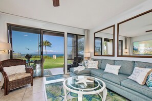 Bright living room with large, sliding glass doors that open directly onto the oceanfront lanai NAP-B13 - Napili Point | Oceanfront 3 BR, Sleeps 10 | Car Incl. w/ 6+ Nights | NAP ML-1550 by KBM (Lahaina)