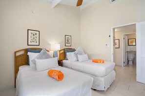 Quarto de hotel com duas camas, uma mesa de cabeceira com abajur e quadros nas paredes.