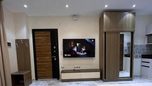 A hotel room with two beds, a TV mounted on the wall, a wooden wardrobe, and a small kitchenette. - Zayed Plaza (Sheikh Zayed City)