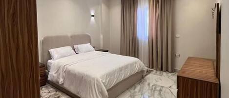 Une chambre à coucher moderne avec un grand lit, une armoire en bois, un tapis à motifs de marbre et un éclairage encastré au plafond.