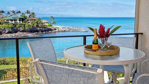 A balcony with a table, chairs, a bottle of champagne, and a vase of flowers. - Napili Point | Oceanfront 5 BR, Sleeps 14 | Car Incl. w/ 6+ Nights | NAP ML-1571 by KBM (Lahaina)