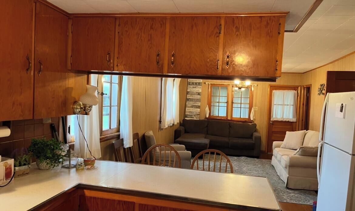 A kitchen with wooden cabinets, a central island, and a dining area with a couch and chairs.
