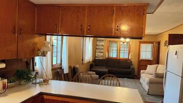 A kitchen with wooden cabinets, a central island, and a dining area with a couch and chairs.