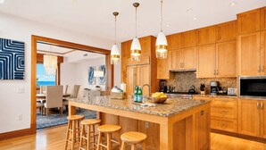 Une cuisine moderne avec des meubles en bois, un plan de travail en granit et un îlot central doté de tabourets.