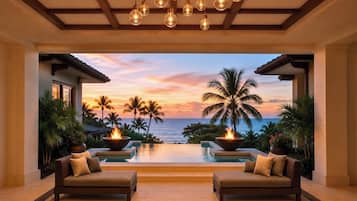 Un área de piscina interior lujosa con vista al atardecer, dos sofás y una chimenea.