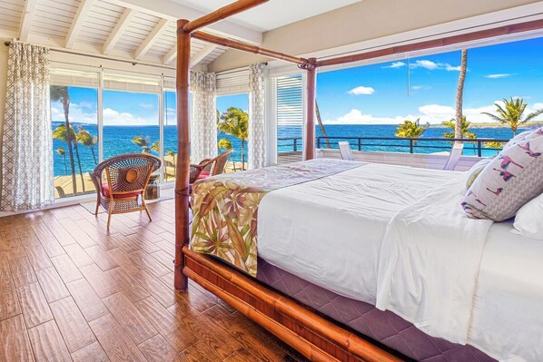 A room with a bed, a chair, and a view of the ocean.