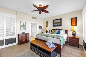 A hotel room with a bed, ceiling fan, bedside lamps, a bench, and a door. - Kapalua Bay | Ocean View 4 BR, Sleeps 12 | Car Incl. w/ 6+ Nights | KBV ML-1601 by KBM (Lahaina)