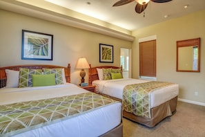 A hotel room with two beds, a ceiling fan, and artwork on the walls.