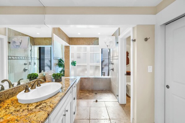 A modern bathroom with a large sink, shower, and a walk-in shower.