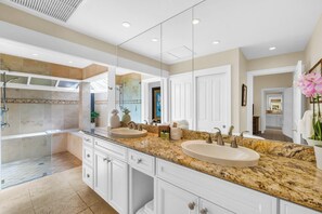 A modern bathroom with two sinks, a shower, and a large mirror.