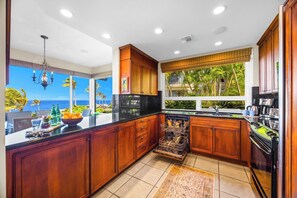 A kitchen with wooden cabinets, a dishwasher, and a view of the ocean.