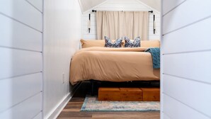 Una habitación pequeña con una cama, un banco de madera y un tapiz estampado.