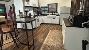 Una cocina acogedora con armarios blancos, techo de madera y comedor con mesa y sillas.