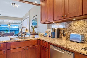 A kitchen with granite countertops, wooden cabinets, a coffee maker, a toaster, and a dishwasher.