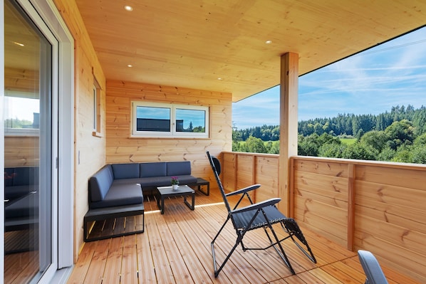 A wooden deck with a sofa, a table, and a chair.