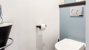 Ein modernes Badezimmer mit einem weißen Waschbecken, einer Toilette und einem Handtuchhalter.