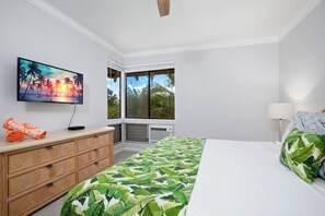 Un dormitorio con cama, televisor en la pared, ventana con vistas y cómoda.