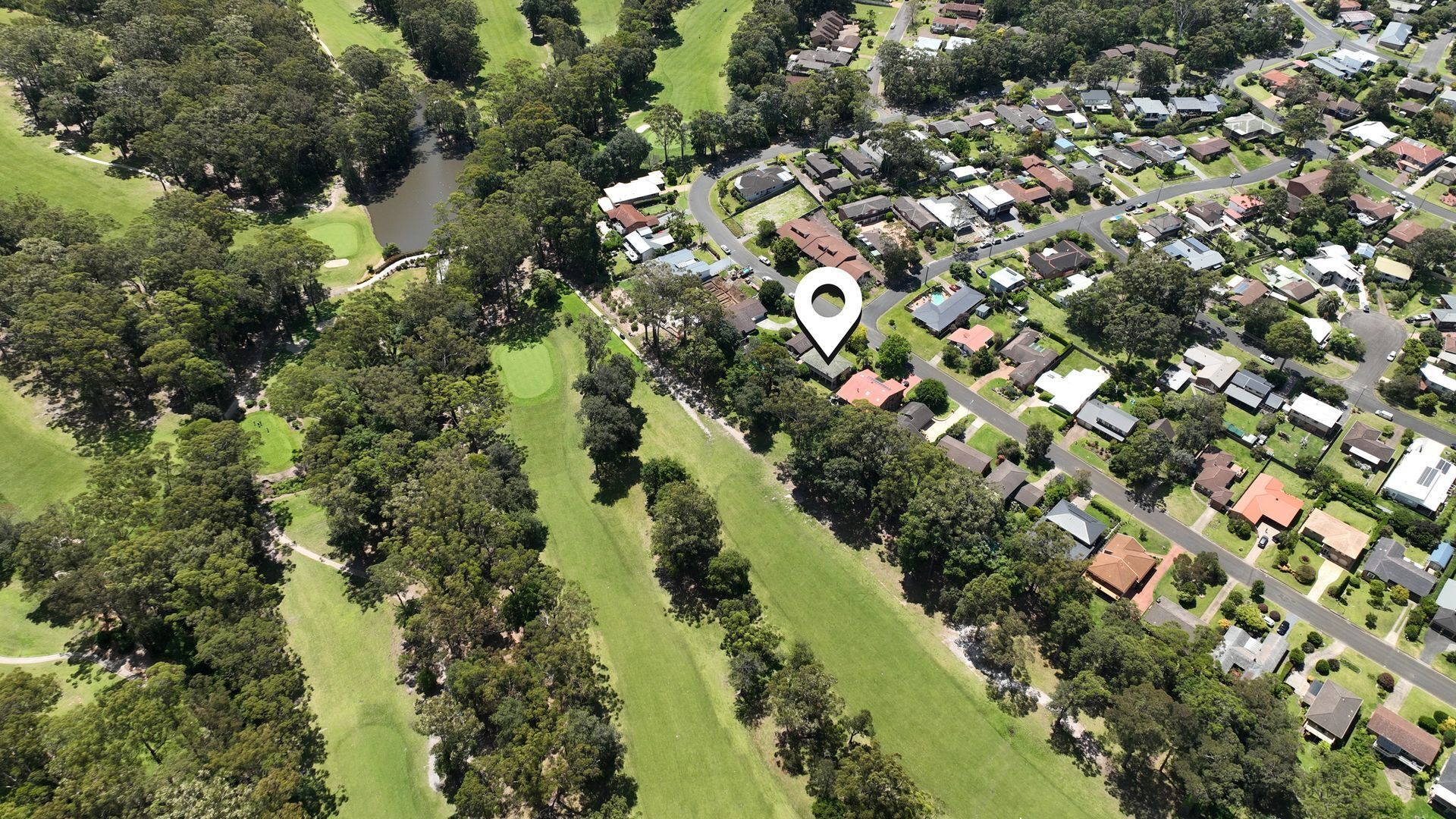 An aerial view of a residential area with houses, roads, and a golf course.