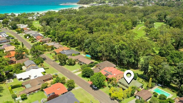 Vue aérienne d’un quartier résidentiel avec des maisons, un terrain de golf et une plage.