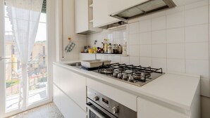 Una cocina moderna con armarios blancos, estufa a gas y ventana con vistas a edificios.
