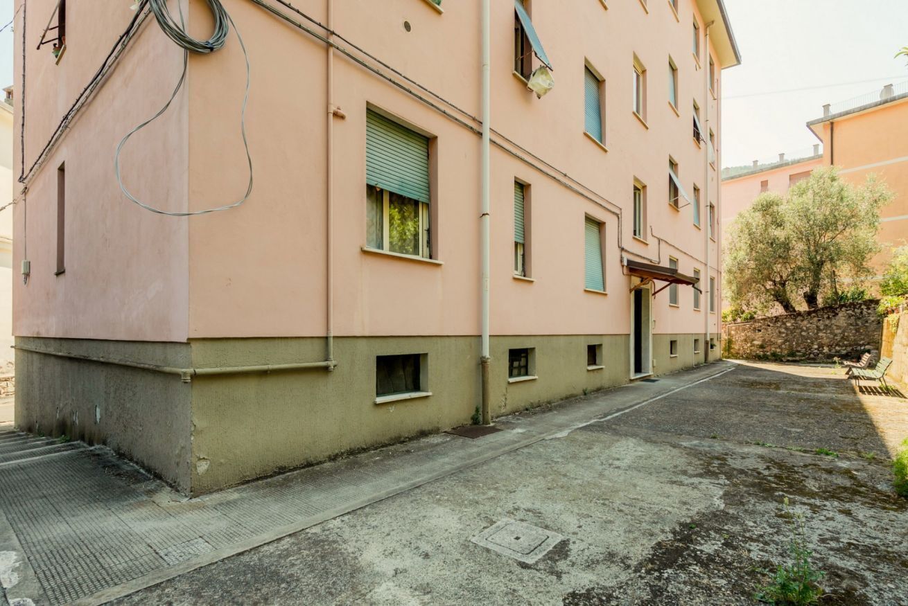 A building with a flat facade, multiple windows, and a paved courtyard.