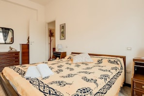 Ein Schlafzimmer mit Bett, Nachttisch, Kommode, Spiegel und Tür.