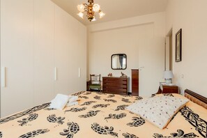 Un dormitorio con cama, cómoda, silla y un espejo en la pared.