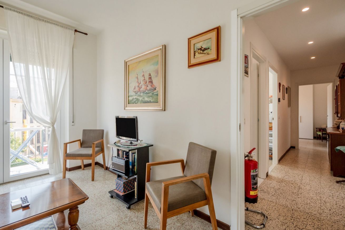A living room with a TV, two chairs, a bookshelf, and a painting on the wall.