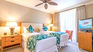 A hotel room with two beds, a ceiling fan, a TV, and a desk with a lamp and phone. - Honua Kai | Ocean View 4 BR, Sleeps 14 | Car Incl. w/ 6+ Nights | HKH ML-1691 by KBM (Lahaina)