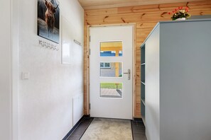 A hallway with a white door, a small window, and a plant on top.