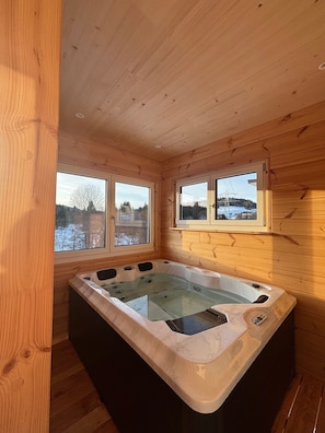 A wooden cabin with a hot tub, large windows, and a view of a snowy landscape. - Mettmapark – Chalet 2 with Private Whirlpool & Sauna, Breakfast Included (Grafenhausen)