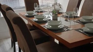 Une table à manger dressée avec des assiettes, des verres et des couverts, entourée de chaises.