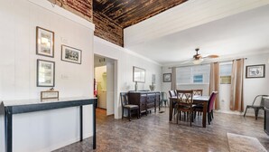A spacious room with a dining table and chairs, a wooden ceiling, and framed pictures on the walls. - Historic Charm in Grand Gulfport Home; walk to beach, casino, port, aquarium (Gulfport)