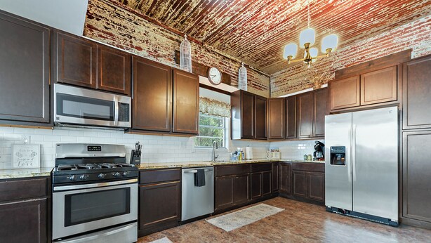 A modern kitchen with stainless steel appliances, dark wooden cabinets, and a rustic ceiling. - Historic Charm in Grand Gulfport Home; walk to beach, casino, port, aquarium (Gulfport)