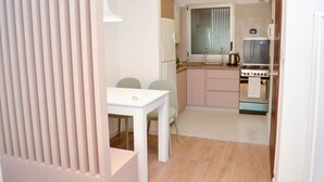 A compact kitchen with a dining table and chairs, a window with blinds, and a stove. - Buenos Aires: Palermo. Perfect for digital nomads. (Buenos Aires)