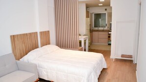 A modern hotel room with a large bed, a sofa, a small table, and a kitchenette in the background. - Buenos Aires: Palermo. Perfect for digital nomads. (Buenos Aires)