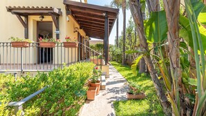 A covered outdoor area with a concrete pathway, potted plants, and a metal railing. - Antonio Family House a Mondello by Wonderful Italy (Palermo)
