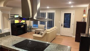 A modern kitchen with a built-in stove, a dining area with a sofa, and a door with a decorative glass panel.
