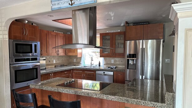 A modern kitchen with stainless steel appliances, granite countertops, and wooden cabinets.