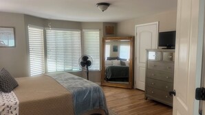 A bedroom with a bed, a dresser, a mirror, and a ceiling fan.