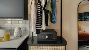 Une cuisine moderne avec un plan de travail blanc, une machine à café et un micro-ondes noir. Des vêtements sont suspendus sur un étendoir placé au-dessus du micro-ondes.