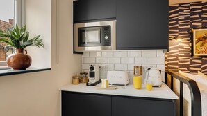 Een moderne keuken met zwarte kastjes, een stalen magnetron, een broodrooster en een koffiezetapparaat.